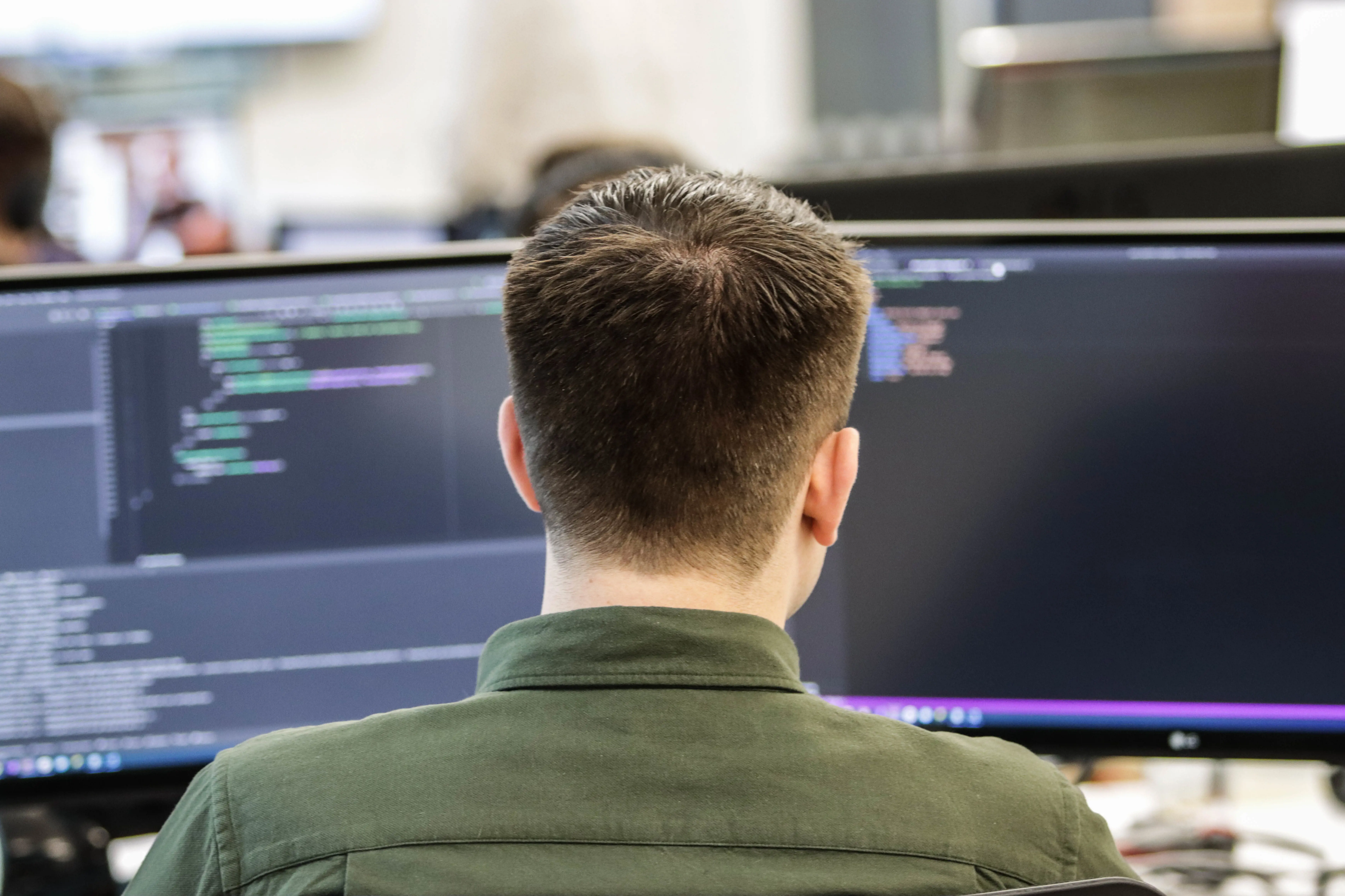 a man from the bag looking at the code on a screen 