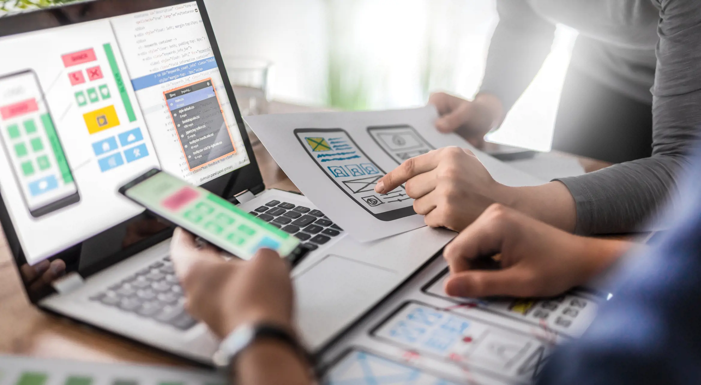 people's hands with laptop, papers with charts and phone diagram 