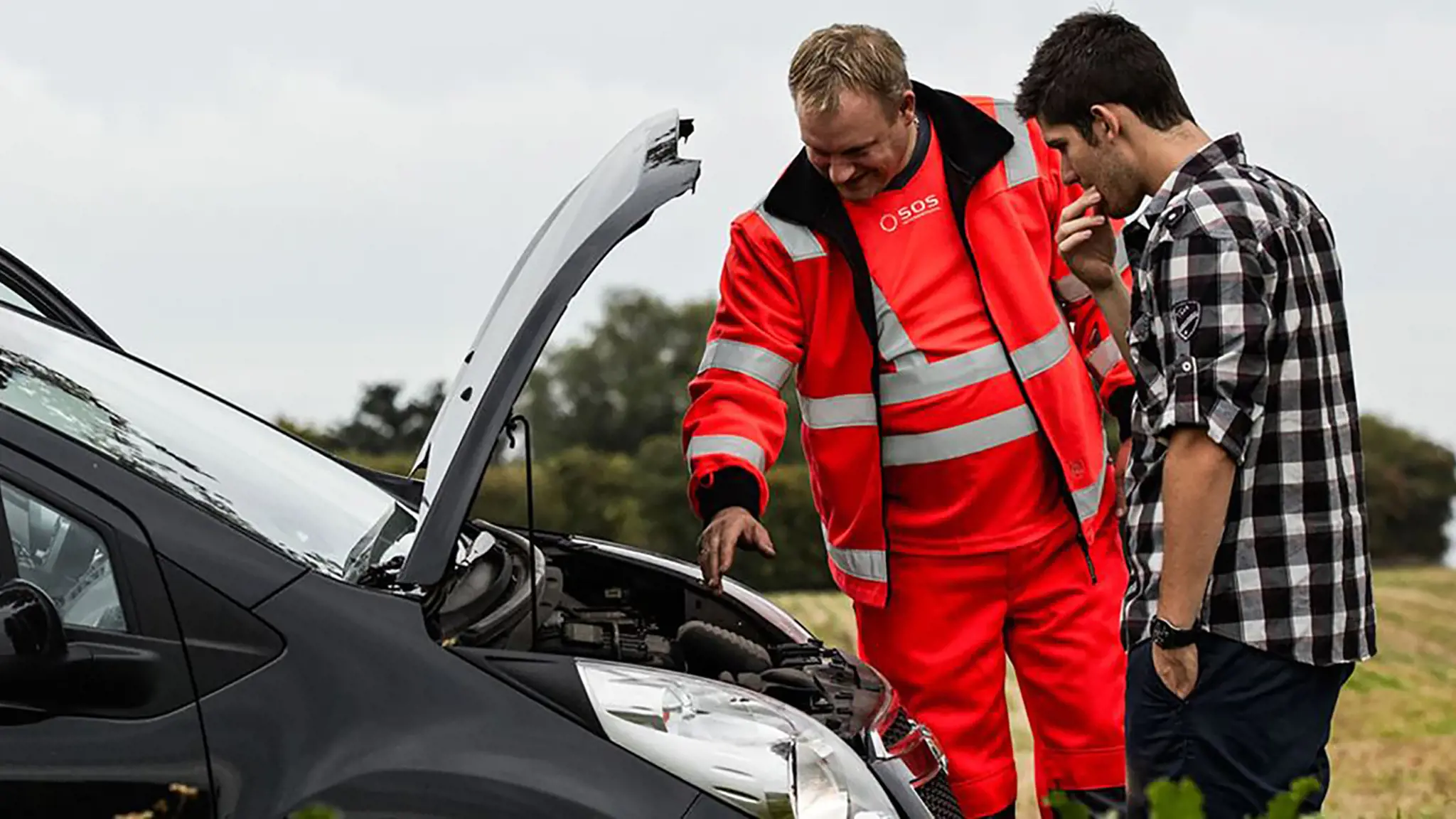 two men looking the open hood of the car