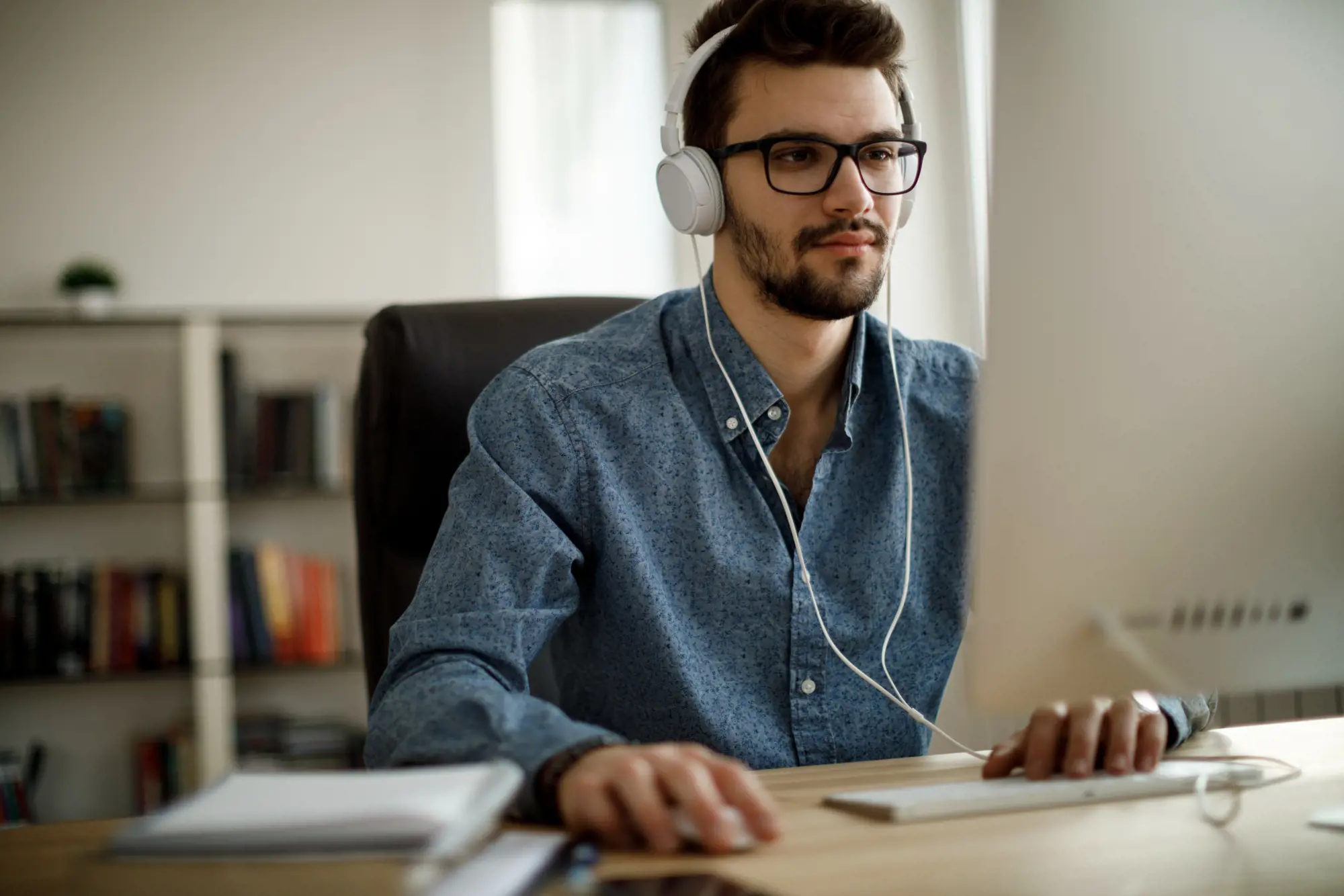 Mand sidder foran computer med høretelefoner | Novicell, Digitalt konsulenthus