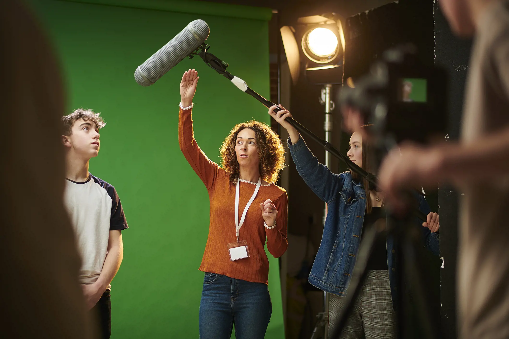 five people working on a production set with a green screen and a boom pole  